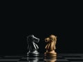 The confront between golden and silver horses, knight chess piece standing together on chessboard on dark background. Royalty Free Stock Photo