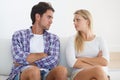 Confrontational couple - relationship issues. A disagreeing couple sitting on a couch together with arms crossed and