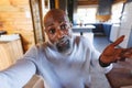 Confused african american bald senior man shrugging his shoulders in log cabin Royalty Free Stock Photo