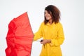 Confused african woman in raincoat close umbrella