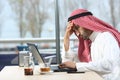 Confused arab man checking laptop in a bar