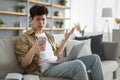 Confused asian man looking at mobile phone using laptop Royalty Free Stock Photo