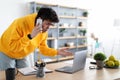 Confused asian man talking on mobile phone using laptop Royalty Free Stock Photo