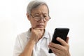 Confused asian senior woman with puzzled looks holding smartphone,confusing by information while using mobile phone or unable to Royalty Free Stock Photo