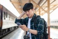 A confused Asian tourist backpacker is checking his train ticket on his phone at a railway station Royalty Free Stock Photo