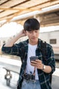 A confused Asian tourist backpacker is checking his train ticket on his phone at a railway station Royalty Free Stock Photo