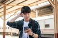 A confused Asian tourist backpacker is checking his train ticket on his phone at a railway station Royalty Free Stock Photo