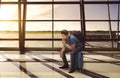 Confused asian tourist sitting on suitcase waiting departure Royalty Free Stock Photo