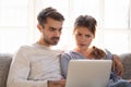 Confused baffled wife and shocked frustrated husband reading online news