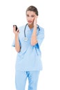 Confused brown haired nurse in blue scrubs using a mobile phone Royalty Free Stock Photo