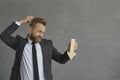 Confused businessman in suit holding arrow down scratching head studio shot Royalty Free Stock Photo