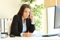 Confused businesswoman talking on phone at office