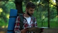 Confused camper orienteering with map in forest, searching for right way