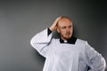Confused catholic priest in white surplice