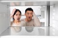 Confused chinese couple looking inside empty fridge at home Royalty Free Stock Photo