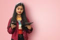Confused Clueless Young Indian Asian teenage girl posing isolated smiling and messaging on mobile phone and tablet using both Royalty Free Stock Photo