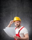 A confused construction worker holding papers or documents