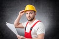 Confused construction worker holding papers