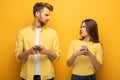 Confused couple with smartphones looking at each other