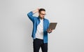 Confused disappointed businessman with hand in hair reading e-mail over laptop on gray background Royalty Free Stock Photo