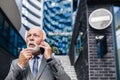 Confused entrepreneur discussing on smart phone while standing against business offices building Royalty Free Stock Photo