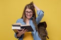 Confused female student with a pile of books rubbing her head troubled with exam