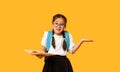 Confused Korean Schoolgirl Holding Book Shrugging Shoulders Over Yellow Background