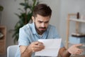 Confused male reading letter shocked by news