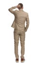 Confused man in beige suit scratching head and thinking Royalty Free Stock Photo