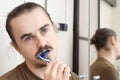 Confused man cleaning his teeth with blue colour Royalty Free Stock Photo