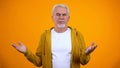 Confused man feeling injustice and helpless, no idea gesture, yellow background