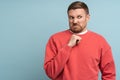 Confused man feels disgust with serious face incredulously looks aside isolated on blue background.