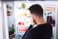 Confused Man Looking At Food In Refrigerator Royalty Free Stock Photo