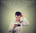 Confused man looking at his mobile smart phone has many questions Royalty Free Stock Photo