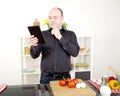 Confused man reading his tablet while cooking