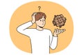 Confused man with wooden puzzle scratches head, wondering how to solve difficult problem Royalty Free Stock Photo