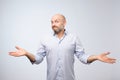 Confused mature bearded man standing and shrugging shoulders isolated over white background. Royalty Free Stock Photo