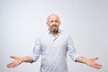 Confused mature bearded man standing and shrugging shoulders isolated over white background. Royalty Free Stock Photo