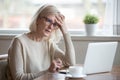 Confused mature woman thinking about online problem looking at l Royalty Free Stock Photo