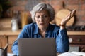 Confused middle aged woman in glasses looking at computer screen.