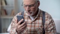 Confused old man looking at cellphone, new technology complicated for elderly