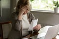 Confused older woman sit at desk look at overdue bill Royalty Free Stock Photo