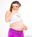 Confused pregnant woman measuring her belly