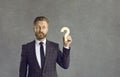 Confused puzzled businessman holding wooden question mark standing on gray on background. Royalty Free Stock Photo