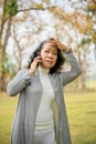 Confused 60s aged Asian woman on the phone, getting lost with her grandchild in the park