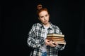 Confused sad young woman student holding books and looking at camera on black isolated background. Royalty Free Stock Photo