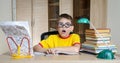 Confused schoolboy in funny glasses screaming near the huge stack of books. Education. Boy Having Problems With His Homework. Royalty Free Stock Photo