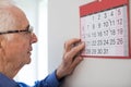 Confused Senior Man With Dementia Looking At Wall Calendar