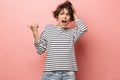 Confused shocked beautiful woman posing isolated over pink wall background pointing