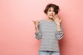 Confused shocked beautiful woman posing isolated over pink wall background pointing